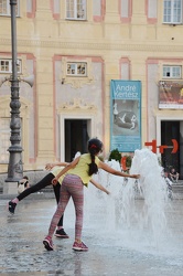 Genova, piazza de ferrari - ragazzini giocano con i getti d'acqu